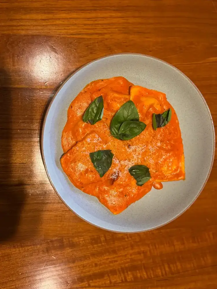 Ravioli in a creamy tomato sauce with basil, seen from above