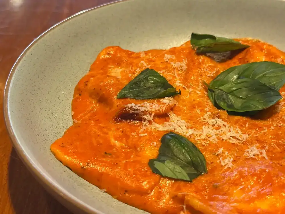Ravioli in a creamy tomato sauce, finished with basil and grated parmesan