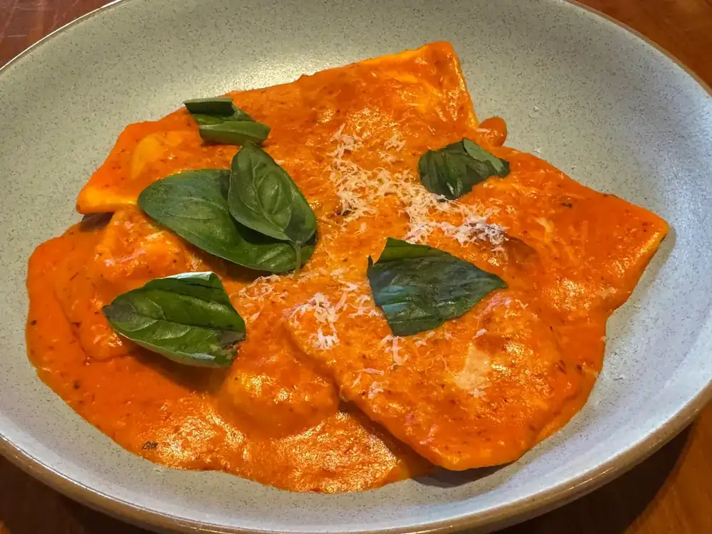 A close-up of ravioli in creamy tomato sauce with fresh basil