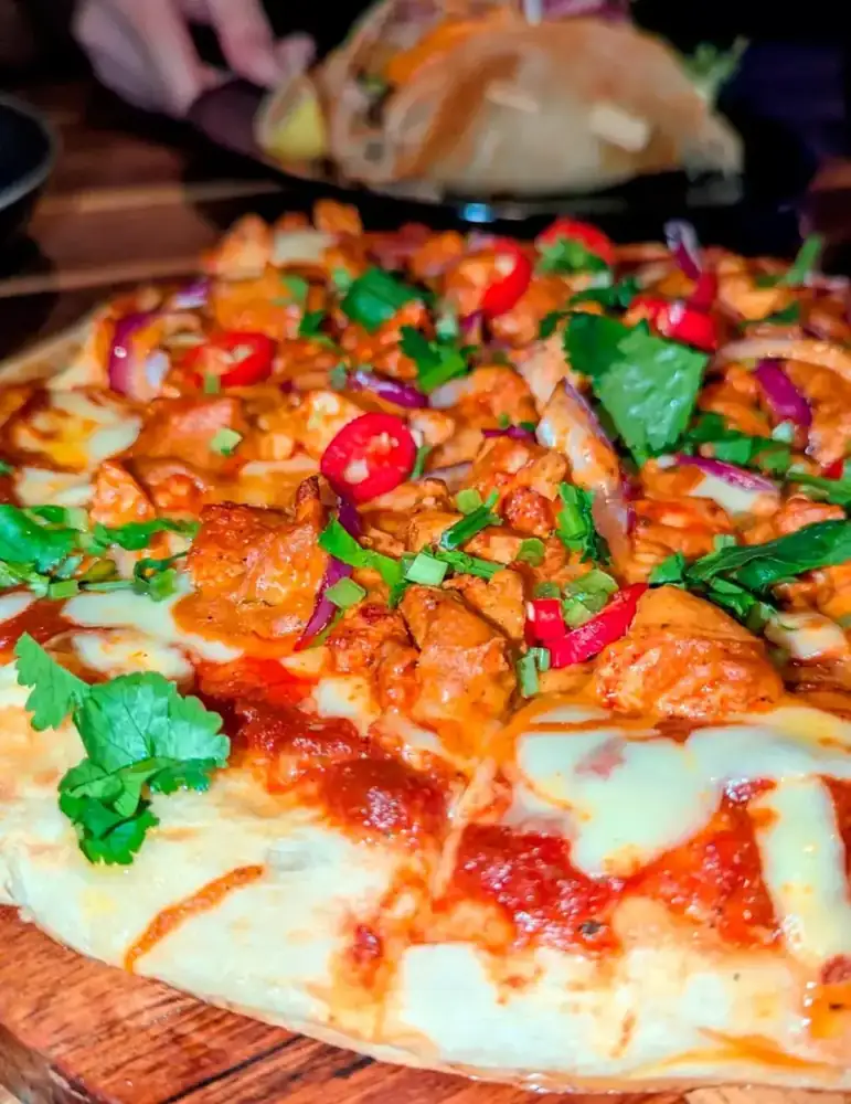 A naan-base pizza topped with chicken, chilli and fresh coriander