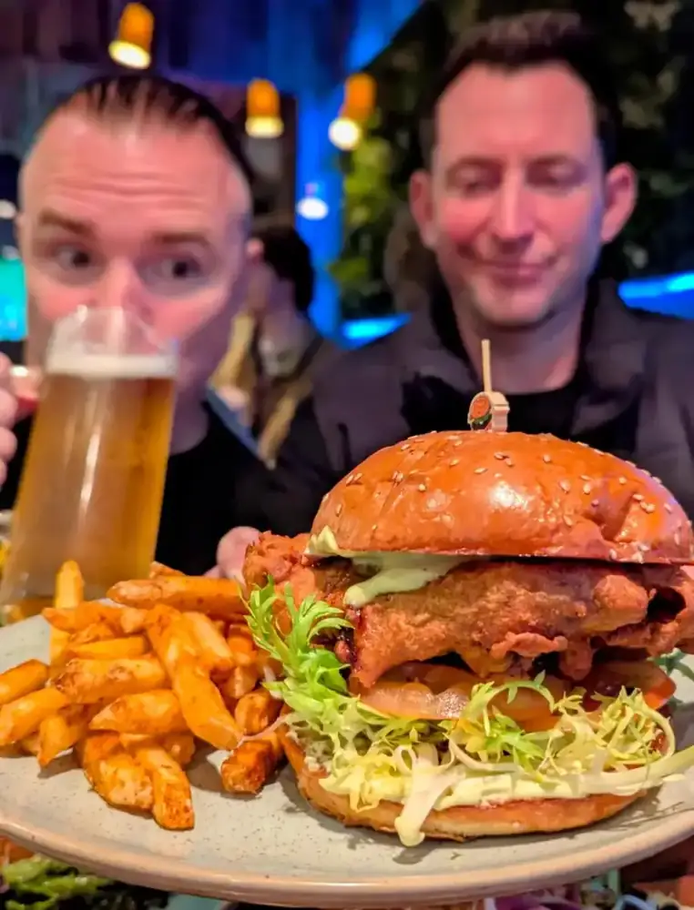 Two guests with a burger and a beer in the dining room