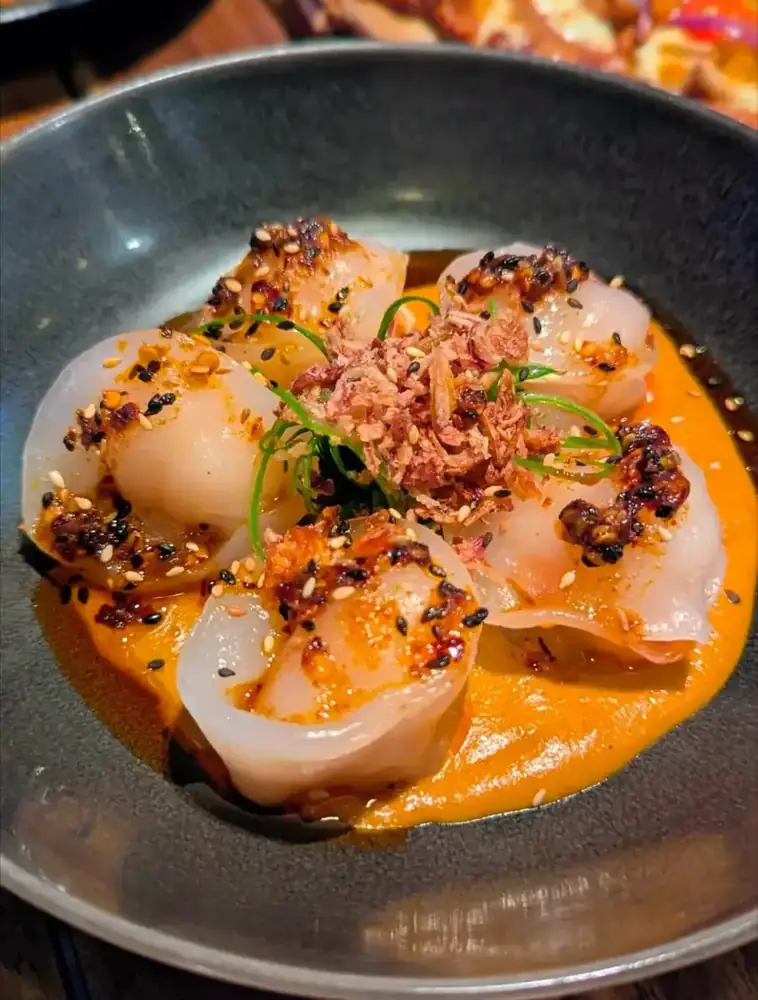 Scallops in a spiced sauce with crisp shallots and toasted sesame