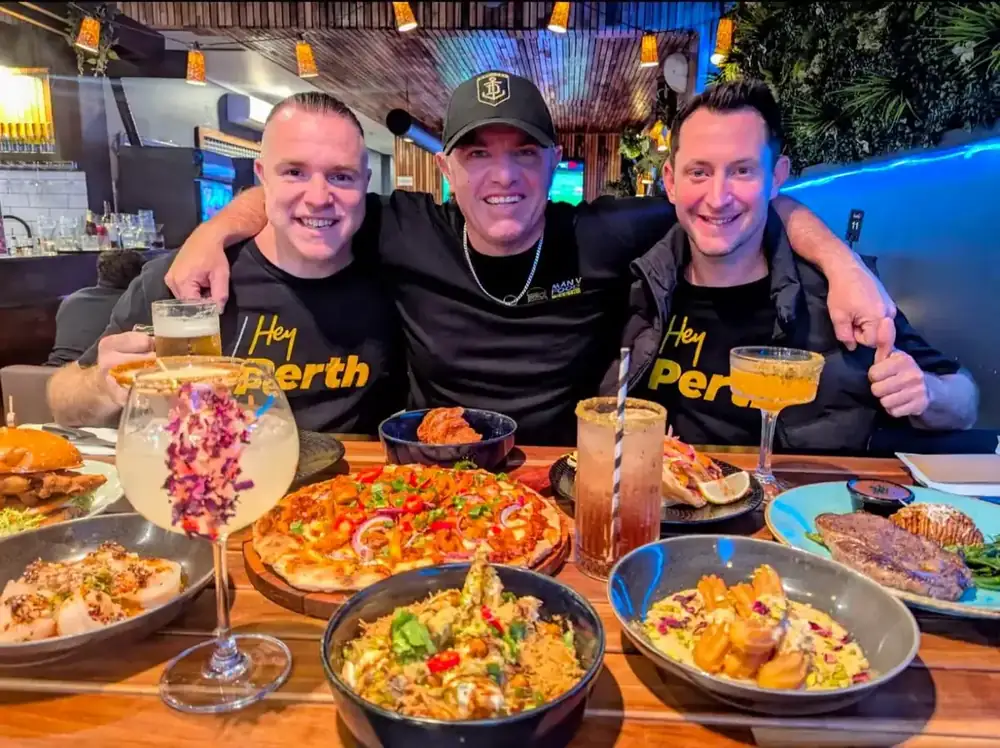 Three guests with a spread of dishes and cocktails